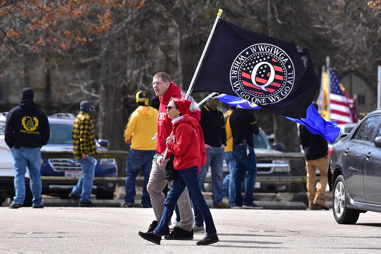 A person holding a QAnon flag at a Raleigh rally